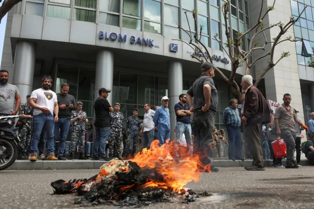 بینک آف لبنان اینڈ اوورسیز کے سامنے جمع کنندگان ٹائر جلا رہے ہیں (رائٹرز)