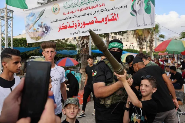 Bir Hamas askeri Gazze’de fotoğraf çekmek için roketatar taşıyan bir çocuğa yardım ediyor (AFP)