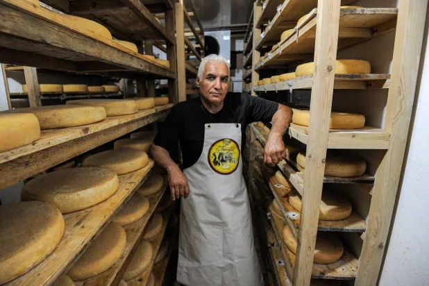 رشيد إبرسين يقف إلى جانب الجبن الذي يصنعه بنفسه في الجزائر (أ.ف.ب)