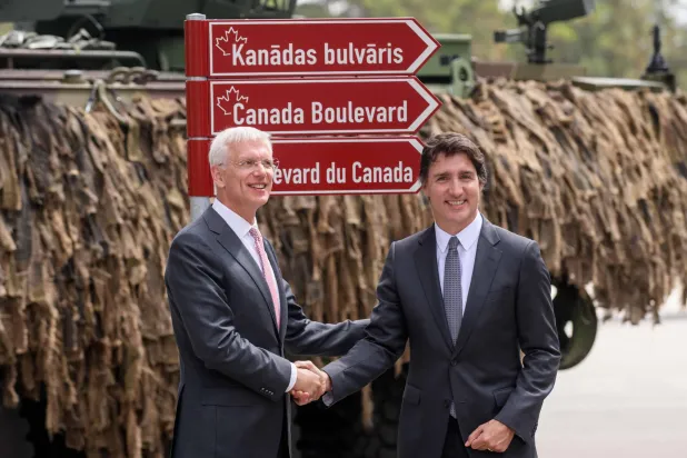 رئيس وزراء لاتفيا كريغانيس كارينش ورئيس الوزراء الكندي جاستن ترودو يتصافحان خلال افتتاح «بوليفار كندا» في قاعدة أدازي العسكرية في ريغا اليوم (أ.ف.ب)