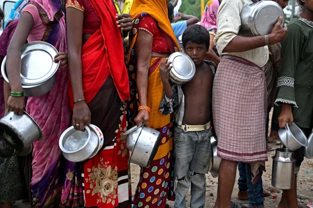 مجموعة من الهنود بانتظار توزيع معونات غذائية في ملجأ طوارئ عقب فيضان أحد الأنهار (أ.ف.ب)