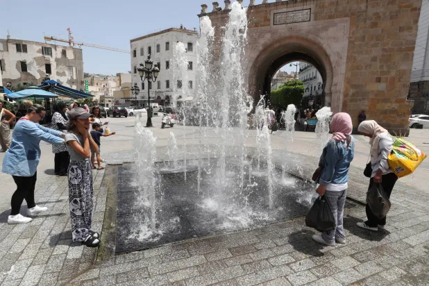 أشخاص يبردون أجسادهم قرب نافورة باب البحر بالعاصمة التونسية (إ.ب.أ)
