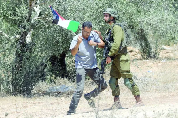 فلسطيني يشتبك مع جندي إسرائيلي خلال مظاهرة ضد التوسع الاستيطاني في قرية بيت ليد قرب طولكرم بالضفة (أرشيفية - إ.ب.أ)