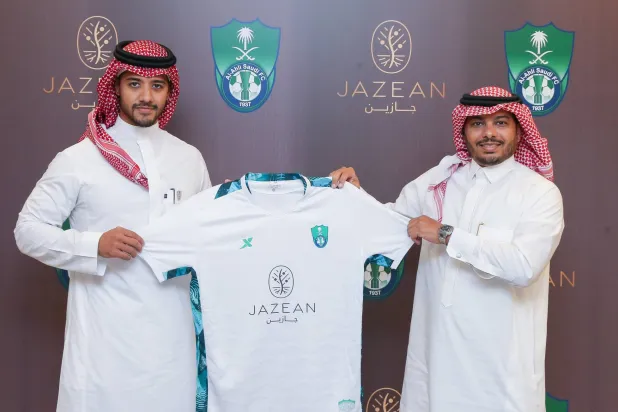 خليفة خلال إهدائه محمد زيني قميصاً تذكارياً للأهلي بعد توقيع العقد (الشرق الأوسط)