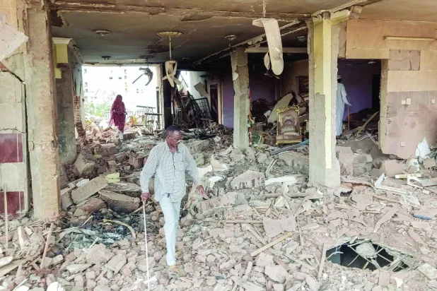 A Sudanese citizen inspects the destruction of a house in the al-Azhari neighborhood south of Khartoum (AFP)