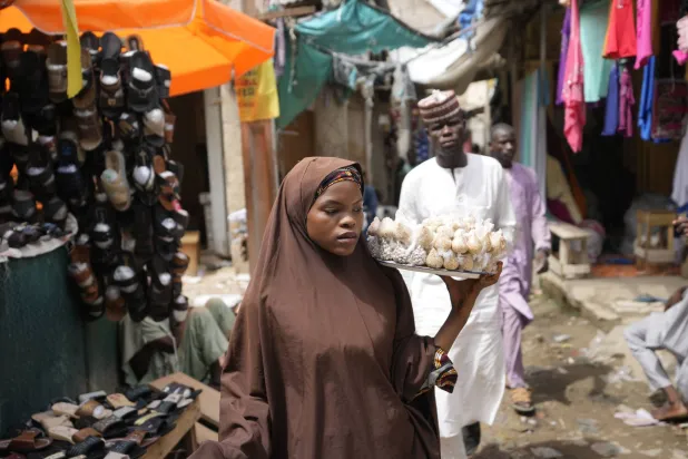 سيدة تبيع مكسرات في سوق بمدينة كانو في نيجيريا 13 يوليو (أ.ب)