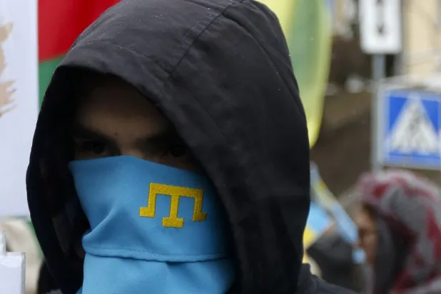 Bir aktivist, 2017’de Ukrayna’nın başkenti Kiev’de, Rusya’nın Kırım’ı ilhakına karşı düzenlenen mitinge Kırım Tatarlarının sembolü olan bir maske takarken (AP)