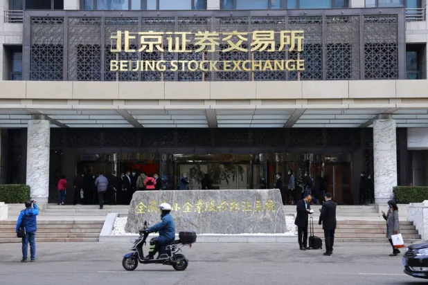 دراجة نارية ومارة أمام بورصة بكين للأوراق المالية (رويترز)