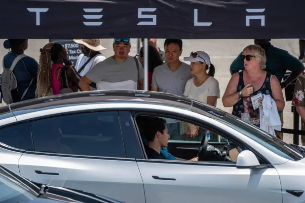 حاضرون يتفحصون سيارة تسلا الكهربائية خلال معرض في واشنطن (أ.ف.ب)