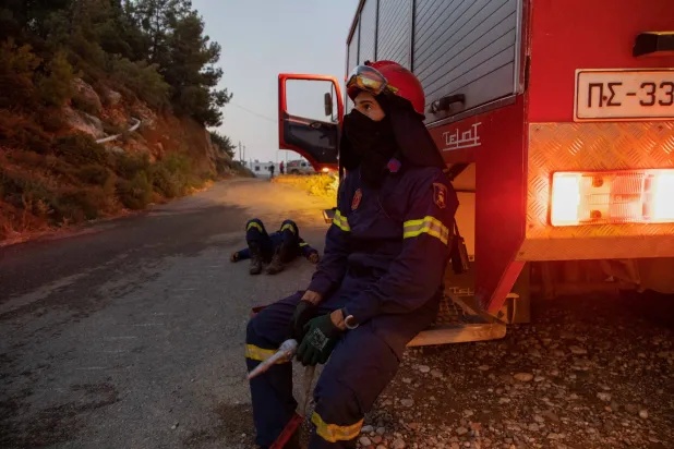رجل إطفاء يرتاح خلال عمله في إطفاء الحرائق بجزيرة رودس (رويترز)