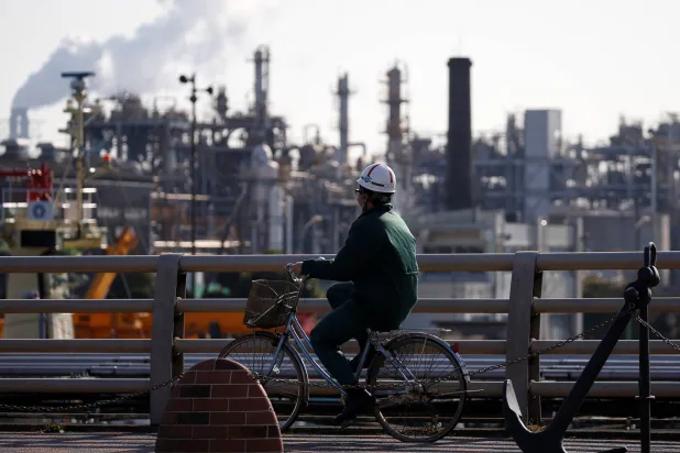 عامل يقود دراجة بالقرب من مصنع في منطقة كيهين الصناعية اليابانية (رويترز)