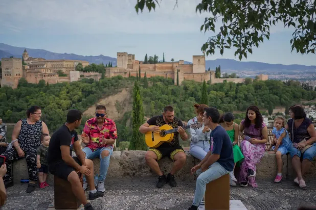 الناس يستمتعون بموسيقى الفلامنكو التقليدية أمام قصر الحمراء في غرناطة (نيويورك تايمز)