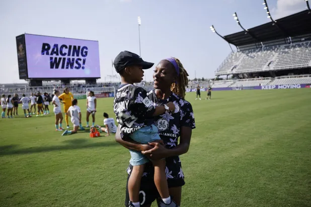 الجامايكية شينا ماثيوز تحمل ابنها في أحد التدريبات (تويتر)