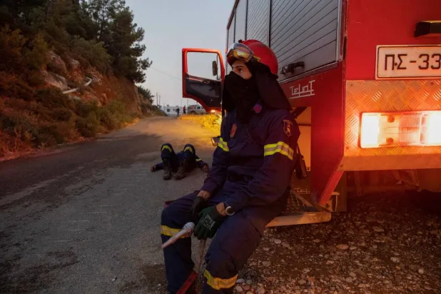 رجل إطفاء يرتاح خلال عمله في إطفاء الحرائق بجزيرة رودس (رويترز)