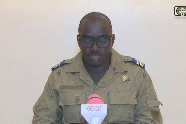 الكولونيل في جيش النيجر أمادو عبد الرحمن يتلو بياناً صحافياً في التلفزيون الوطني الجمعة 28 يوليو 2023 (أ.ف.ب)
