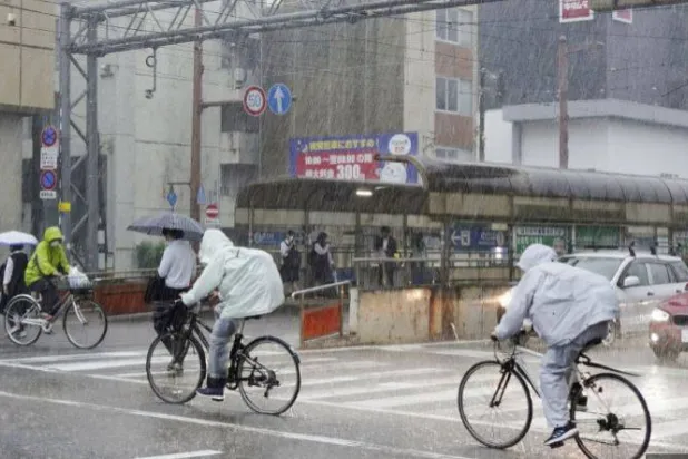 أشخاص يركبون دراجات وسط الأمطار الغزيرة في كوتشي باليابان (أرشيفية - رويترز)