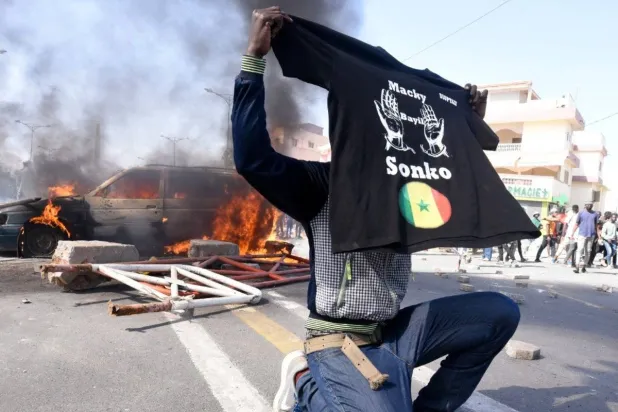 أحد أنصار عثمان سونكو يرفع قميصاً يحمل اسمه في مظاهرات يونيو (حزيران) الماضي (رويترز)