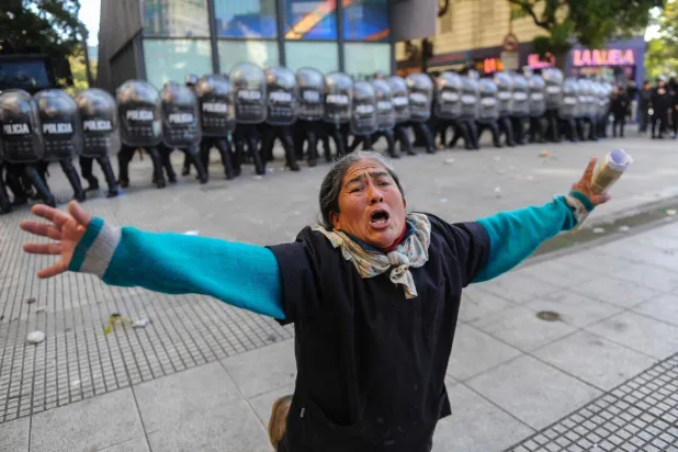 Arjantin'de bir kadın, protestoculara polise taş atmayı bırakmaları için yalvarıyor / Fotoğraf AFP