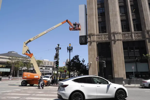 عمال يزيلون ما تبقى من شعار «تويتر» على مبنى الشركة في كاليفورنيا (إ.ب.أ)