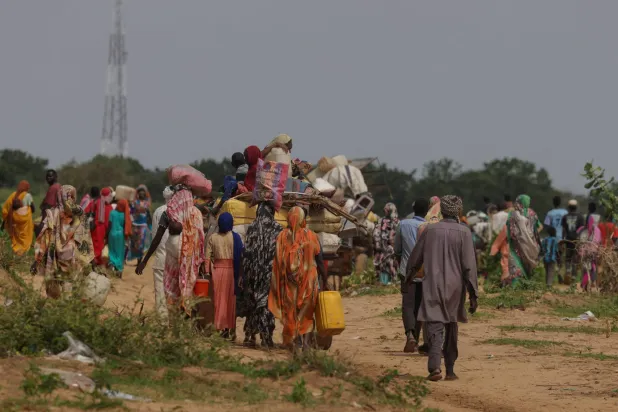 سودانيون فروا من الصراع بمنطقة دارفور السودانية يسيرون بجوار عربات تحمل أمتعتهم عند عبورهم الحدود بين السودان وتشاد في أدري بتشاد في 2 أغسطس 2023 (رويترز)