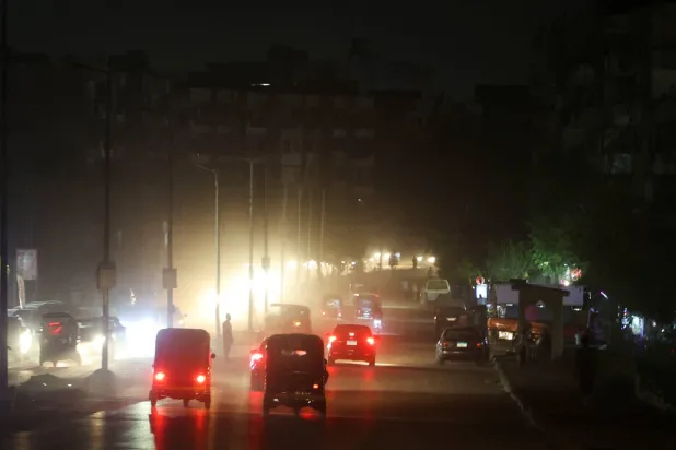 مركبات وأشخاص يسيرون في طرق مظلمة بالقاهرة (رويترز)