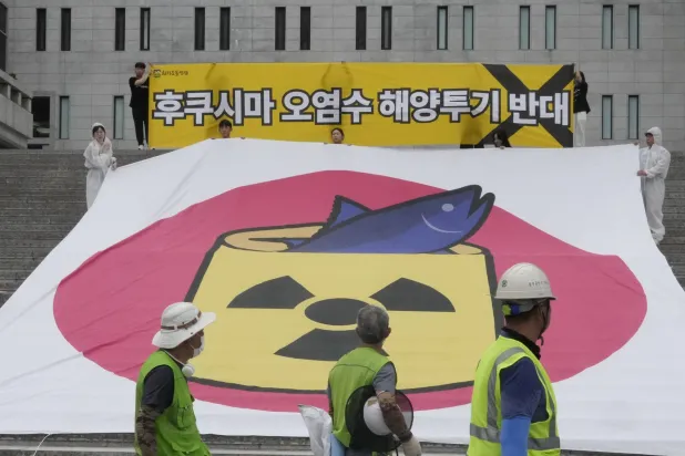 نشطاء بيئيون خلال مسيرة في سيول رفضاً لخطة الحكومة اليابانية تصريف مياه من محطة فوكوشيما النووية (أ.ب)