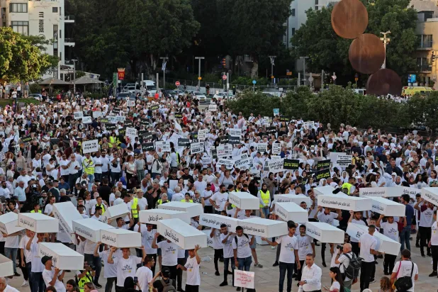 توابيت رمزية يحملها عرب إسرائيل في تل أبيب احتجاجاً على جرائم العنف بالمجتمع العربي (أ.ف.ب)