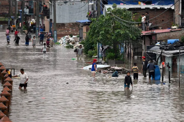 السكان يسيرون على طول طريق غمرته المياه في كاتماندو (أ.ف.ب)