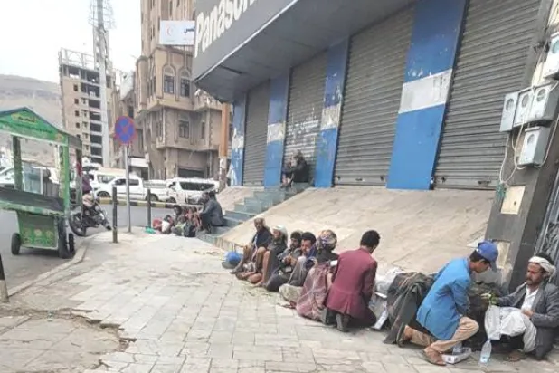 يمنيون يصطفون على رصيف شارع بصنعاء بحثاً عن عمل (الشرق الأوسط)