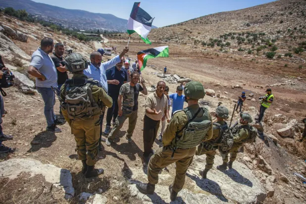 Nablus yakınlarındaki yerleşim birimlerine karşı düzenlenen gösteride İsrail askerleri Filistinli protestocuların önünde duruyor (dpa)