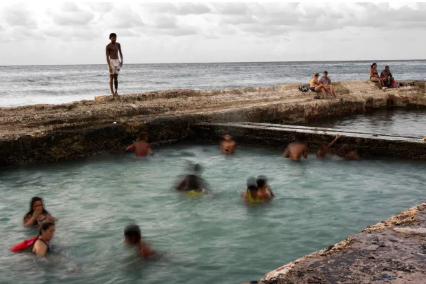 المسابح المعروفة فقط للسكان المحليين تقع في نهاية ممشى مليء بالنفايات (أ.ف.ب)