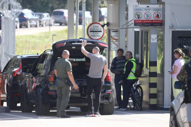 فحص سيارة عند نقطة العبور في بلدة شومسكاس الليتوانية عند الحدود مع بيلاروسيا قبل أيام من القيود الجديدة (أ.ف.ب)