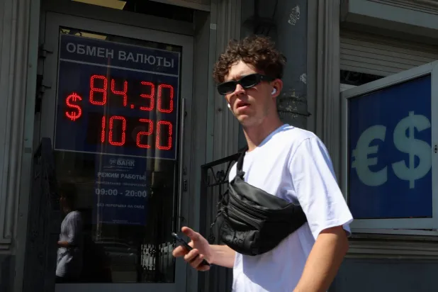 رجل يسير بالقرب من لوحة تعرض أسعار صرف الدولار مقابل الروبل في سانت بطرسبرغ (رويترز)