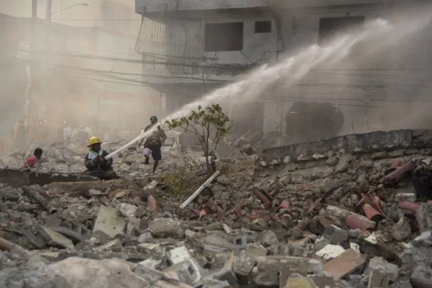 رجال الإطفاء يحاولون إخماد الحريق الناجم عن الانفجار في سان كريستوبال (أ.ب)