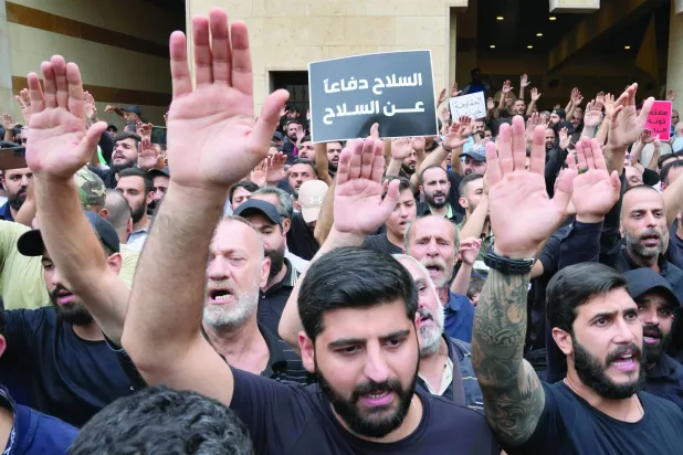 "ہتھیاروں کے دفاع میں ہتھیار"..."حزب اللہ" کے ارکان نے الکحالہ  قصبے میں مارے گئے اپنے ایک ساتھی کے جنازے کے دوران نعرہ بلند کر رہے ہیں (اے پی)