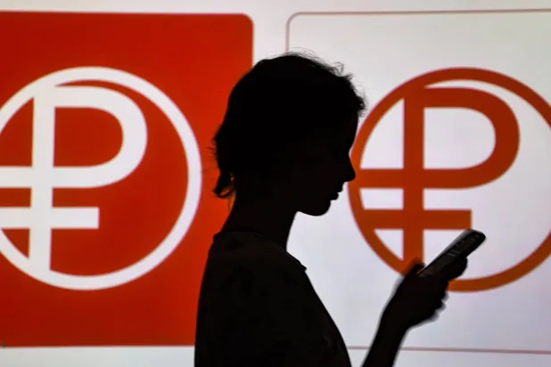 سيدة أمام رمز الروبل الرقمي الروسي في موسكو (إ.ب.أ)
