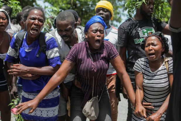 سكان حي كارفور فوي يتجمعون خارج قاعدة عسكرية للمطالبة بالمساعدة بعد أن اضطروا للفرار من منازلهم عندما سيطرت العصابات عليها (رويترز)