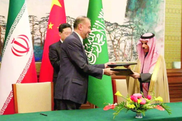 وزير الخارجية السعودي الأمير فيصل بن فرحان ونظيره الإيراني حسين أمير عبداللهيان يتبادلان وثيقة الاتفاق بعد التوقيع في بكين (رويترز)