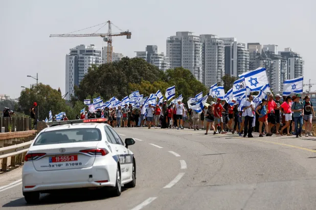 مظاهرة ضد خطة الإصلاح القضائي قرب حفل افتتاح خط السكك الحديدية السريع لمنطقة تل أبيب الخميس (رويترز)