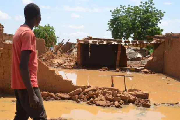 مواطن نيجري أمام بيوت طينية دمرتها الفيضانات (أرشيف - أ.ف.ب)