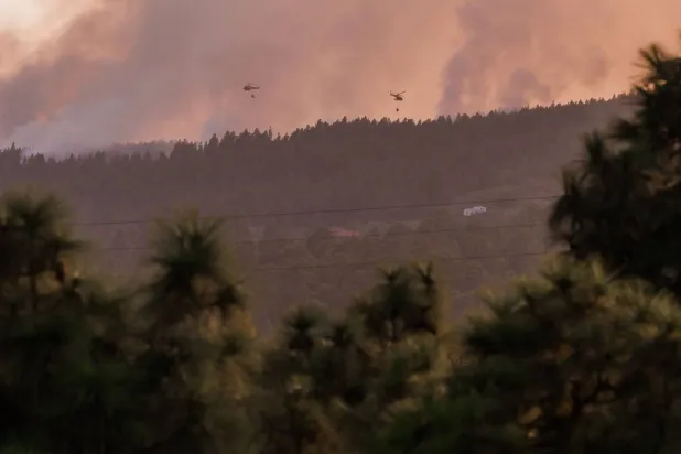 طائرات هليكوبتر تسقط المياه في منطقة غيلمار فوق حريق غابات ضخم يستعر في مناطق الغابات التي تحيط بمنتزه بركان جبل تايدي الطبيعي في جزيرة تينيريفي بجزر الكناري في إسبانيا في 21 أغسطس 2023 (أ.ف.ب)