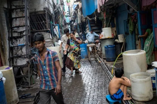 مشاة في أحد أزقة حي فقير بمدينة مومباي الهندية (رويترز)