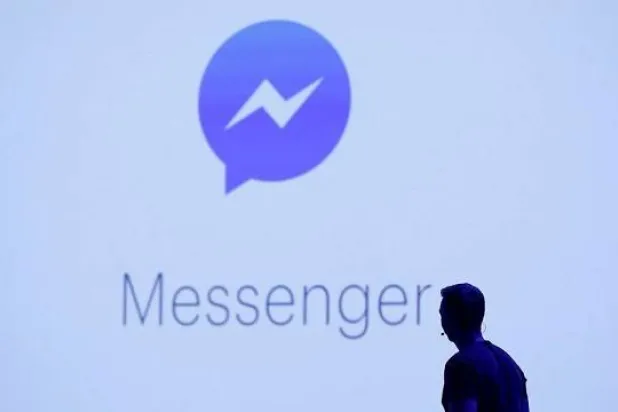 شخص يقف أمام شعار لتطبيق «ماسنجر» (أرشيفية - رويترز)