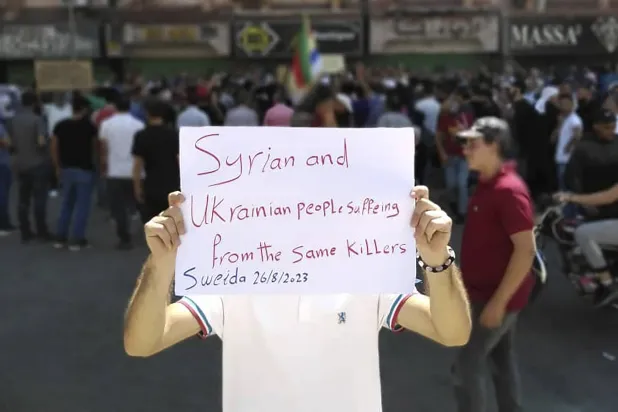 في هذه الصورة التي نشرها «السويداء 24» رجل يحمل لافتة في احتجاج مدينة السويداء السبت  (أ.ب)