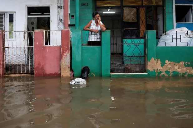 امرأة تقف أمام منزلها وسط فيضانات في منطقة باتابانو بمقاطعة مايابيكي بكوبا (أ.ف.ب)