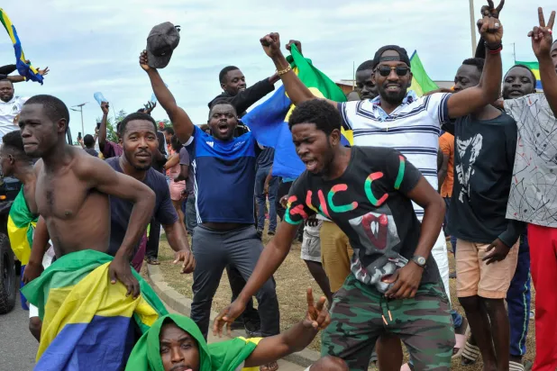 متظاهرون يرفعون علم الغابون في شوارع أكاندا (إ.ب.أ)