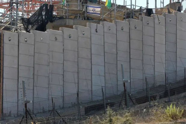 اسرائیلی فوجی لبنان کے ساتھ سرحدی باڑ کے پیچھے اپنی پوزیشنوں پر ہیں اور سرحد کے لبنانی جانب UNIFIL سائٹ کا نشان (اے ایف پی)