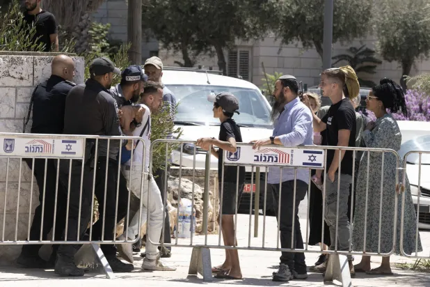 مستوطنون إسرائيليون يشاهدون الشرطة وهي تعتقل ناشطاً يسارياً في مظاهرة بالقرب من منزل وزير الأمن القومي اليميني المتطرف إيتمار بن غفير (أ.ب)