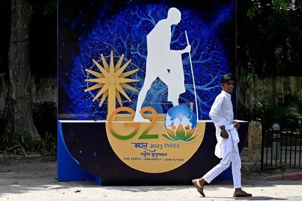 رجل يمر عبر عرض ترويجي تم إعداده لقمة مجموعة العشرين قبل افتتاحها، على طول شارع في نيودلهي (أ.ف.ب)
