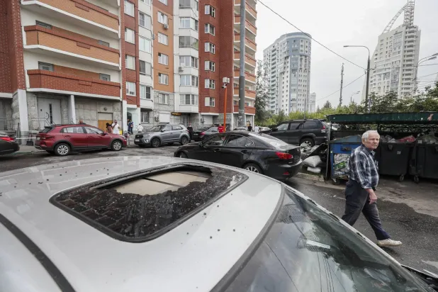 Moskova bölgesindeki Krasnogorsk'ta hasarlı arabanın yanından geçen bir adam, 22 Ağustos 2023. (EPA)